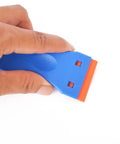Hand holding 1.5 Inch Plastic Razor Scraper With Ten Double Edged Blades For Removing Labels, Stickers, And Decals From Glass Windows