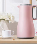 Grab And Go Kickass Vacuum Insulated Travel Thermos With Secure Silicone Lid Locks In Scalding Heat Or Ice Cold Temperatures All Day Long Killer For Daily Commutes pink stainless steel thermos on wooden table with coffee cup and flowers