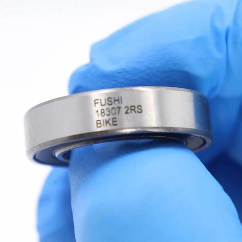Close-up of Sealed Cartridge Bearing Set 18 X 30 X 7 mm MR18307 RS 5 Pack for Bike Hubs with visible engraving, held in blue glove