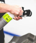 Person using a spray bottle with a brush on a car mat; product similar to All In One Car And Workshop Universal Cleaner Highly Concentrated