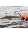Angler holding Dock Runner Spinning Reel And Fishing Rod Combo 36 Inch Medium Action Multi Piece Rod Setup with lake background
