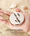 Front view of Neosmuk fishing magnet with lifting ring, chrome finish, held in hand on sandy beach.