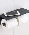 Stainless Steel Double Toilet Paper Holder With Shelf Wall Mounted Matte Black Finish displaying two rolls and a phone.