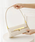 Beige shoulder handbag with gold turn-lock clasp and strap