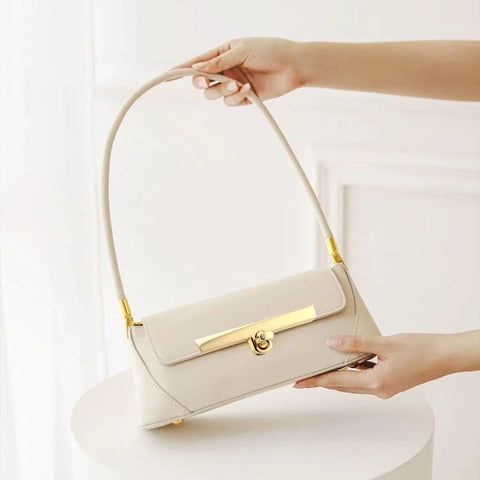 Beige shoulder handbag with gold turn-lock clasp and strap