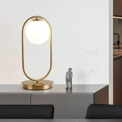 Dope Gold Globe Table Lamp With White Glass Shade For Bedside And Desk Mid Century Modern Style on a sideboard