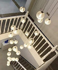 Modern Round Glass Ball Chandelier With Long Stair Pendant Light Featuring Heavy Duty Steel Frame And Premium Glass Orbs For Easy Ceiling Setup And Killer Room Glow hanging above staircase.