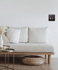 Radiant 450W Preset Decorator Rocker Dimmer Switch With LED Locator on white wall above sofa, dark bronze finish RH453PDBCCV6.