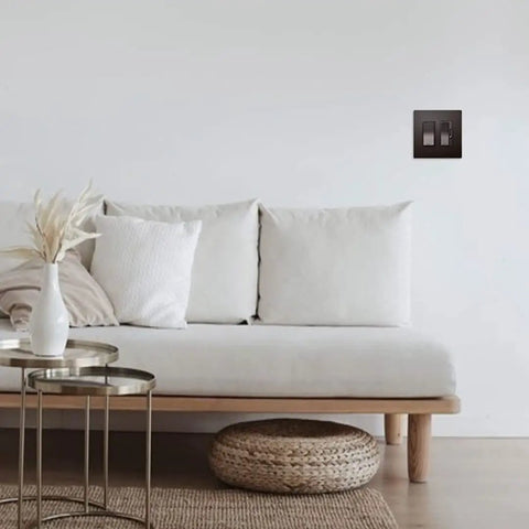 Radiant 450W Preset Decorator Rocker Dimmer Switch With LED Locator on white wall above sofa, dark bronze finish RH453PDBCCV6.
