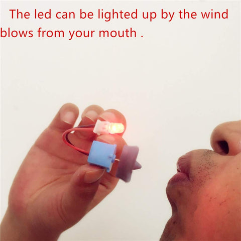 Close-up of person blowing on small Wind Hydroelectric Generator Model For STEM Classrooms, LED lights up demonstrating AC wind power