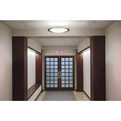 Emergency APC7R Combo Unit LED Exit Sign With Dual Lights Red Letters For Safer Hallways In Damp Locations visible above doors in hallway.