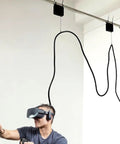 Person using VR headset with ceiling cable suspension system for immersive experience indoors.