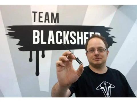 Person holding Crossfire Micro Receiver V2 Super Tiny Lightweight UHF Long Range For Mini And Micro Quads in front of logo.