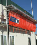 Titan Pump Jack Safety Net, 22 ft long, orange netting with Titan logo, mounted on exterior scaffold.