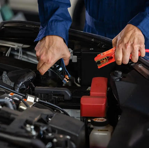 Person using 16 Foot Heavy Duty Jumper Cables 6 Gauge Automotive Booster Cables to connect battery terminals in vehicle engine.