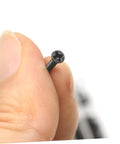 Close-up of a tiny black machine bolt in hand from the Top Shelf Miniature Small Screw Assortment Kit With Transparent Organizer Box And Tiny Machine Bolts Perfect For Nitty Gritty Repairs And Weekend Projects Gonna Need This One.