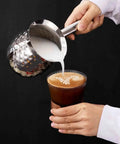 Stainless steel cezve pouring milk into coffee, demonstrating use of Turkish Coffee Pot Cezve Ibrik 200ml Stainless Steel Stove Top Brewer.