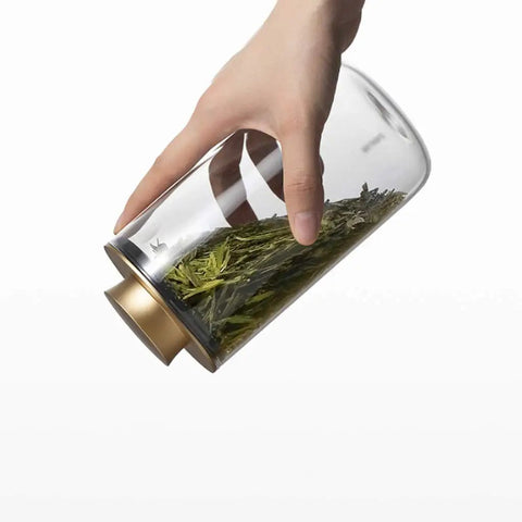 Top Notch Slick Large Glass Kitchen Jars Set Of Four Aluminum Lids with loose tea inside, held by a hand for easy access.
