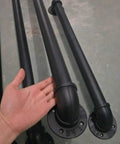 Straight Up Industrial Pipe Stair Handrail Featuring A Rock Solid Non Slip Grip Built Tough For Hallways And Lofts Delivering Daily Safety For Every Home Setup - black iron pipes close-up with hand for scale.