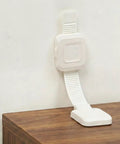 Heavy Duty No Drill Furniture Anchors For Baby Proofing With Upgraded Adhesive Straps mounted on a wall with a white strap.