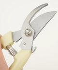 Hand holding heavy duty branch pruning shears with stainless steel blades and drop forged handles for cutting garden plants.