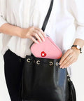 Person placing Pink Mini Outdoor First Aid Kit Bag For Travel And Everyday Use into black handbag