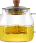 Glass teapot with wooden lid, brewing yellow herbal tea, featuring a stainless steel infuser inside the transparent pot.