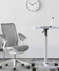 Hella Sturdy Height Adjustable Mobile Standing Desk With Smooth Glide Casters And Rustproof White Steel Top Portable Laptop Workstation And Rolling Podium For Home Office Space beside a modern ergonomic chair.