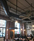 Industrial 8 Ft HVLS Ceiling Fan Featuring Brushless Motor Built in VFD and Remote Control with Savage Airflow in a trendy café setting.
