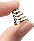 Close-up of hand holding stainless steel spring from Universal Stainless Steel Quick Release Skewer Springs Kit For Mountain And Road Bikes 10 Pack Durable Hub Lever Springs For Secure Wheel Attachment Rust Resistant And Easy To Install.
