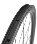 Close-up of a carbon fiber rim on a 38mm Tubeless Disc Brake Road Wheelset 700c Carbon Fiber Toray T700 With 25mm Rim Shimano 8 To 12 Speed UCI Approved And EN Certified Lightweight Beast For Fast Climbs And Smooth Descents 2 Year Warranty.