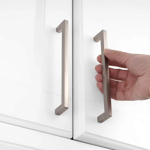 Hand installing 20 Pack Brushed Nickel Square Bar Cabinet Handles Set With Easy Install Six Point Three Inch 160mm Screw Hole Distance Solid Metal Hardware For Kitchen Cabinets Cupboards Bedroom Dressers Drawers Wardrobes Plus Free 25mm And 38mm Screws on white cabinet doors.