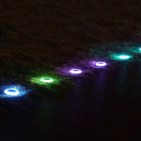 8 Pack Solar Ground Lights With 20 Lumen White And Color LED Disk Lights Multi Color Modes illuminating a garden pathway