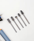 Five tungsten carbide rotary burrs from the 10-Piece Tungsten Carbide Rotary Burr Set With Blue Case For Metal Deburring And Wood Carving High-Precision Grinding And Polishing Bits For CNC Routers Hobbyists And Professionals Tackling Intricate Edges on a white background.