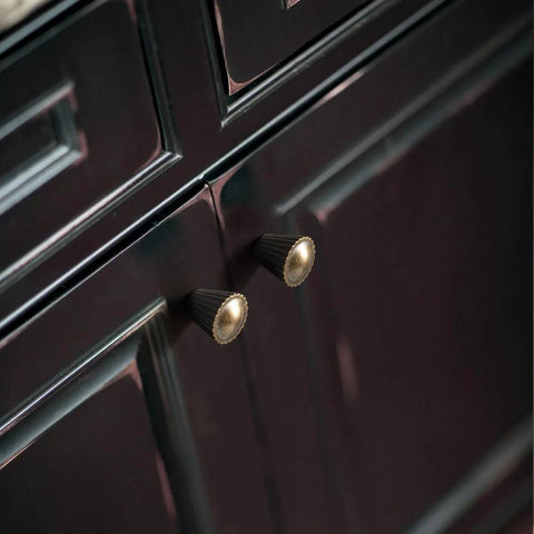 Six Pack Antique Brass Cabinet Knobs With Fluted Trumpet Ends installed on dark cabinetry