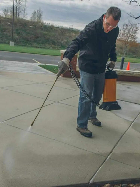 Man using a sprayer to apply Tough As Nails Penetrating Concrete Sealer For Driveways And Retaining Walls Breathable Moisture Shield.