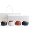 Handcrafted Ceramic Tea Canisters With Airtight Wooden Lids Keep Your Daily Stash Locked In This Rock Solid Porcelain Storage Set Of Four For Modern Home Kitchens. Four ceramic jars in black, white, red, and blue with wooden lids.
