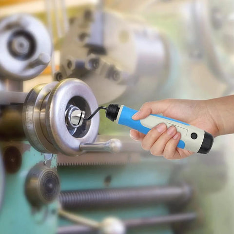 Side view of a blue-and-white handheld deburring tool being used on a metal lathe workpiece.