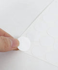 580 Piece Self Adhesive Screw Hole Stickers Set For Wooden Furniture And Cabinets, PVC Cover Caps Dustproof, 12mm 15mm 21mm, White, 6 Sheets, Easy Install For A Clean, Seamless Look shown close-up on white background with hand applying sticker