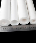 Four heavy duty PTFE sleeve 50cm hollow tubes with varying inner holes, next to a ruler for scale, designed for industrial use.
