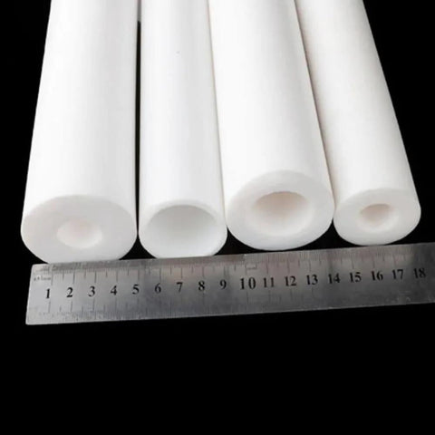 Four heavy duty PTFE sleeve 50cm hollow tubes with varying inner holes, next to a ruler for scale, designed for industrial use.