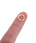 Close-up of a single golden copper washer on a finger, part of the 40Pc Copper Flat Washer Set For Oil Drain Plugs And Hydraulic Lines.