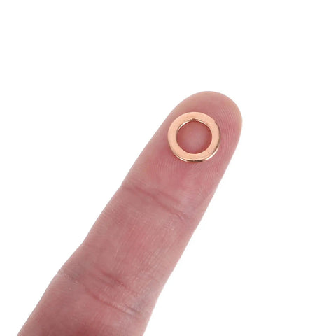 Close-up of a copper washer on fingertip, part of 40 Piece Copper Washers For Brake Lines And Hydraulic Systems Pro Grade Sealing Gasket Set