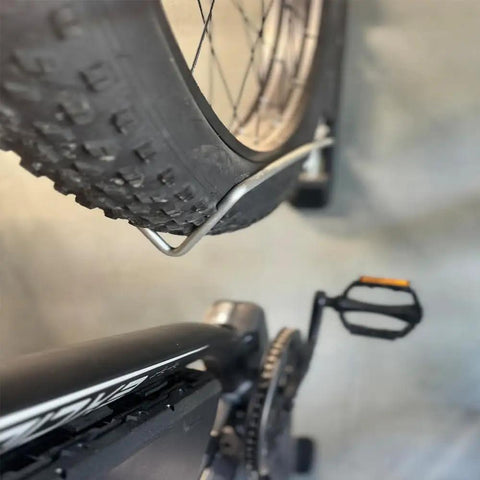 Close-up of Swivel Wall Mount Bike Rack For Indoor Storage With Space Saving Design And Swivel Arms holding a bike tire.