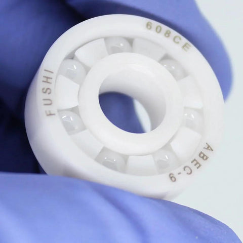 Close-up of white 608 zirconia full-ceramic ball bearing held by gloved hand