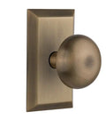 New York Round Door Knob with Studio Plate in Brushed Nickel shown in a warm brass finish on white background.