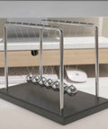 7 Ball Desk Pendulum Cradle With Glass Base And Stainless Steel Balls on an office desk, solid wood frame