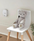 Plug In Carbon Monoxide Alarm With Battery Backup, Electrochemical Sensor, 85 Decibel Alarm on wall above chair with toy bear
