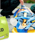 Zoll AED Plus defibrillator in bright green case beside patient on a stretcher