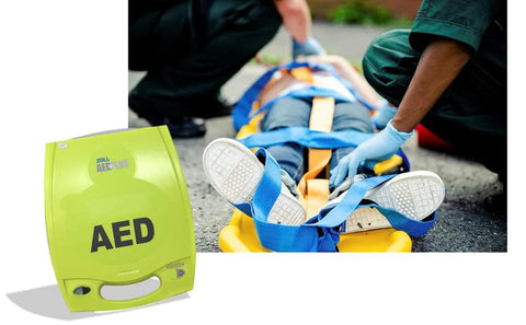 Zoll AED Plus defibrillator in bright green case beside patient on a stretcher